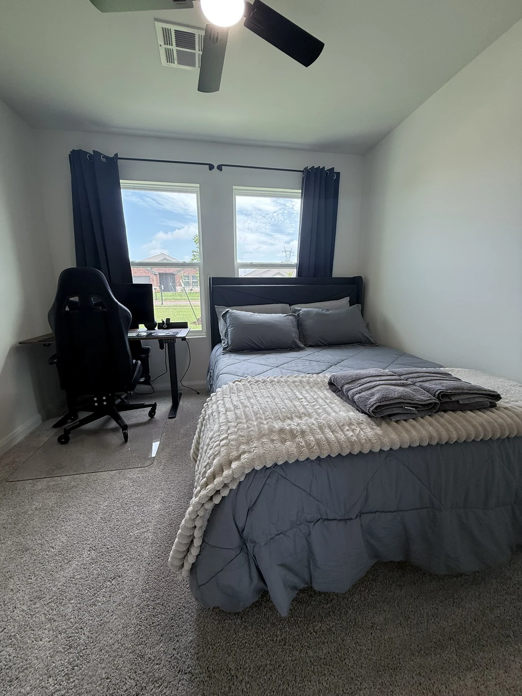 A complete private bedroom with bed, blackout curtains, desk, monitor, and chair
